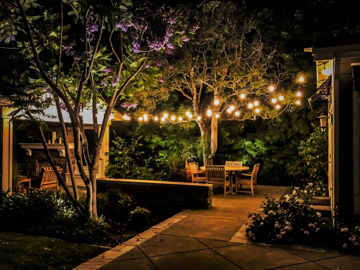 A string-lit garden patio glowing under the oak trees at night in the South Austin Entertainment District